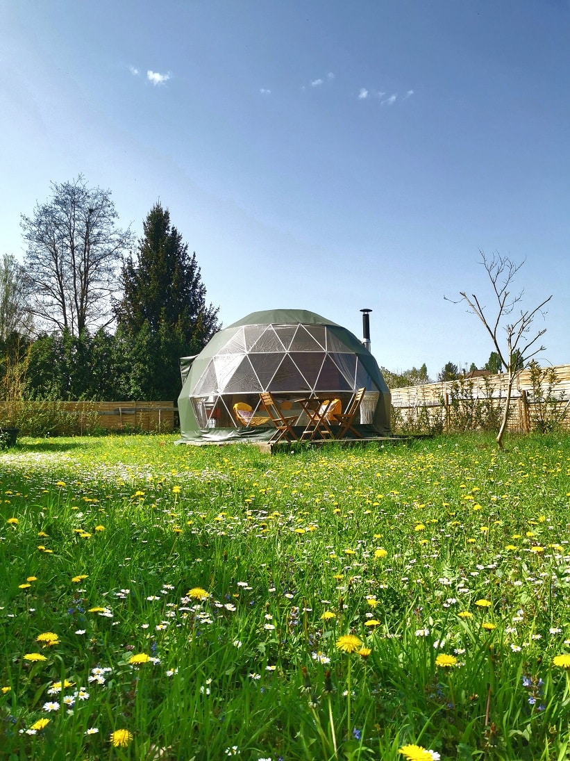 Vue romantique du Dôme de l’Aube dans un jardin de pommiers, un cadre paisible pour un séjour intime.